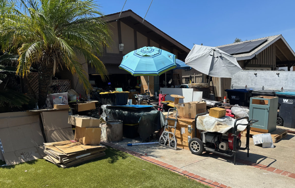 Front yard of a Mission Viejo home with stored items and containers visible near the driveway